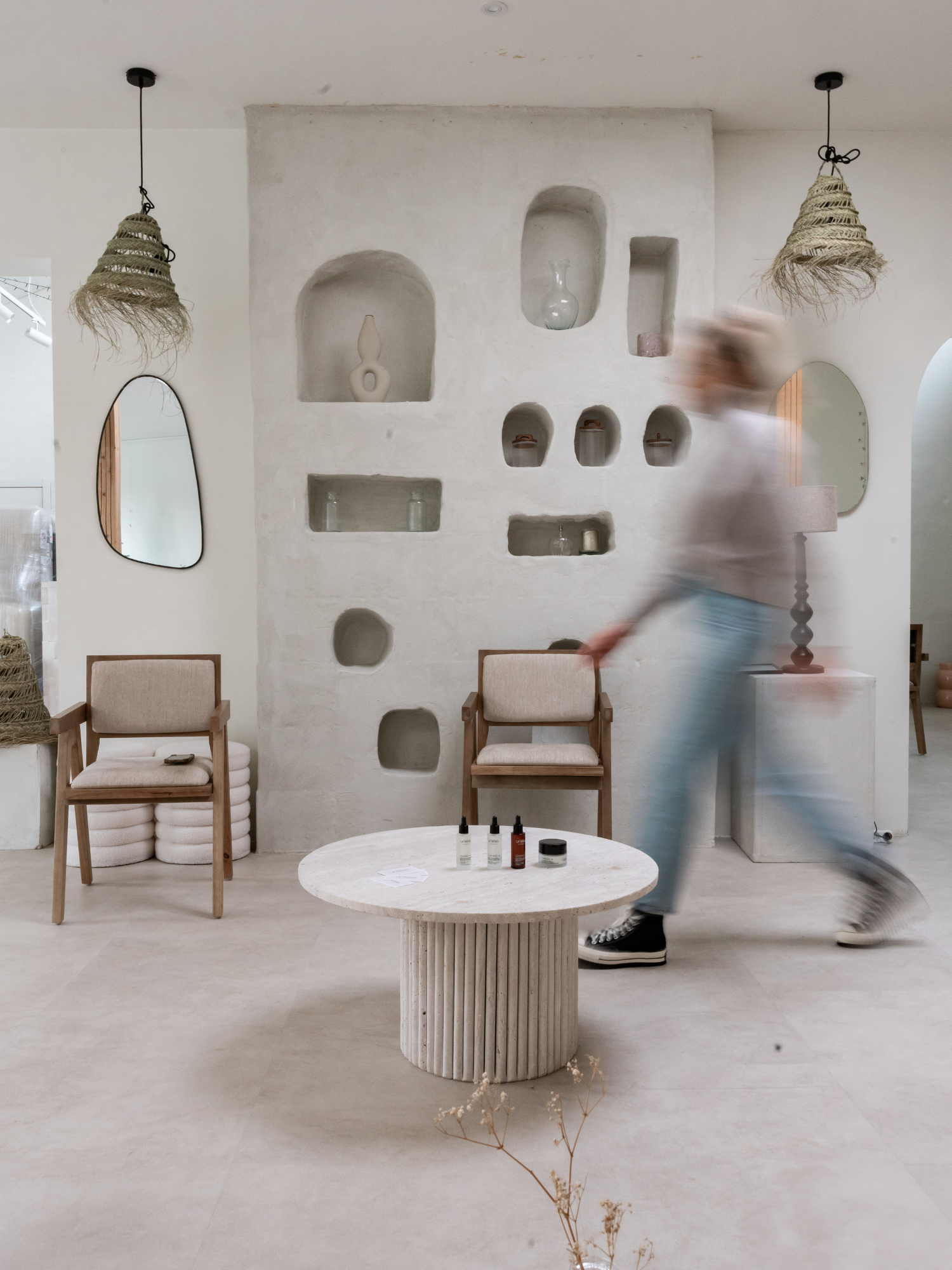 Femme floutée marchant en arrière-plan, derrière des produits Unlëss Cosmetics posés sur une table au premier plan.