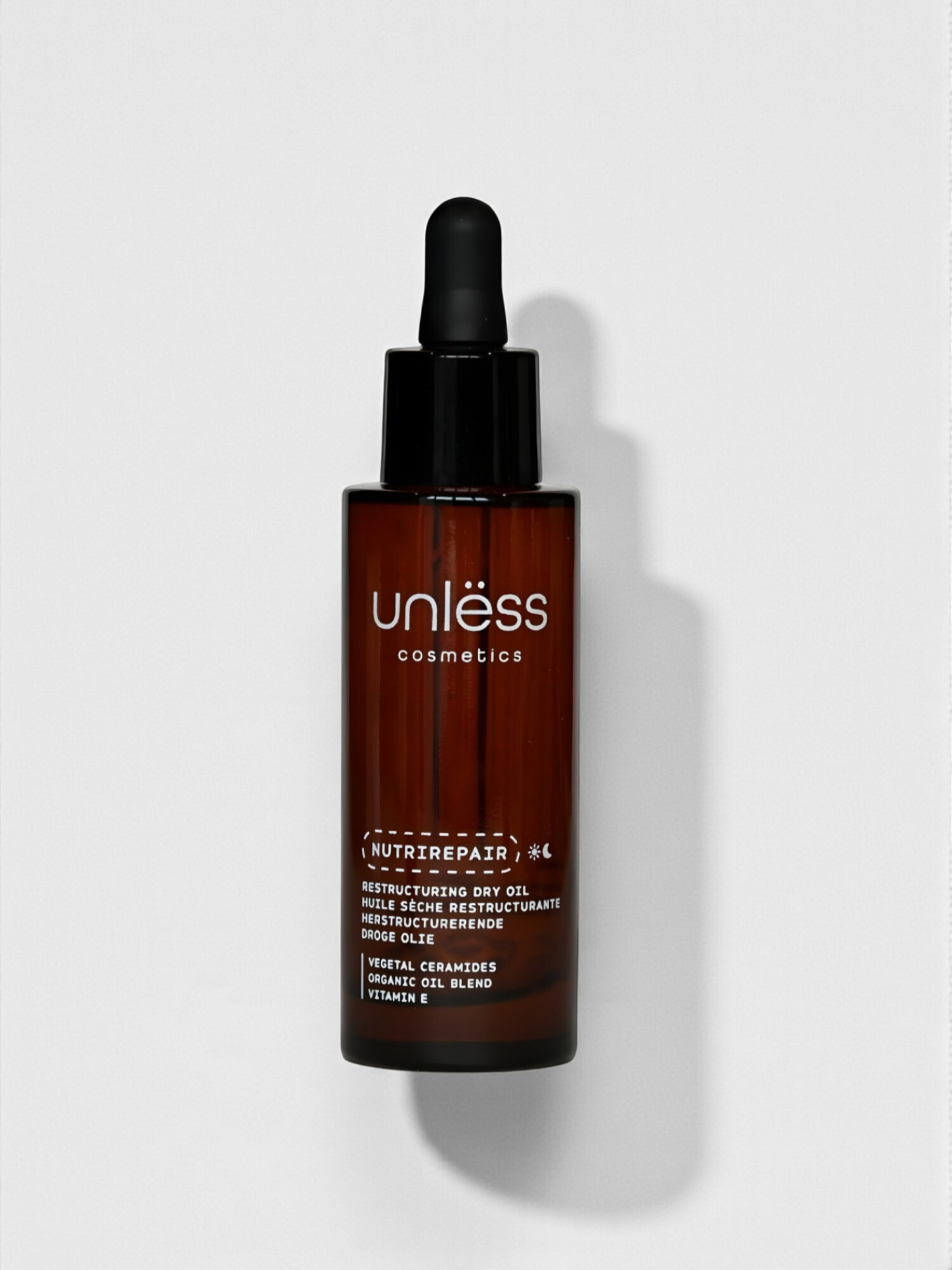 Flacon de l’huile Nutrirepair d’Unlëss Cosmetics posé sur fond blanc avec son ombre projetée.
